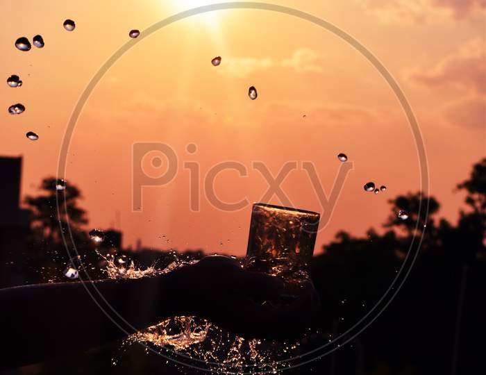 Water Splash Image Of Water Being Thrown Out Of A Glass In Evening Sunset