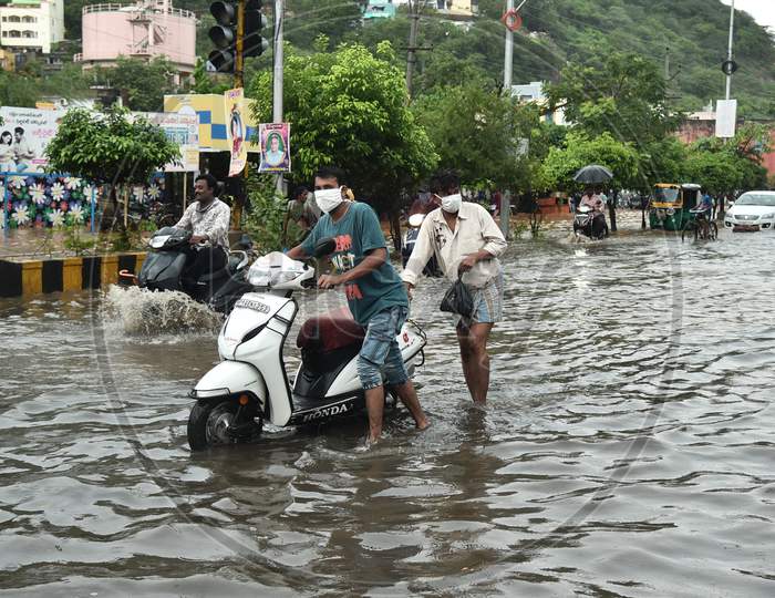 Commuters Wade Through A Water-Logged Road During Heavy Rain In Vijayawada.