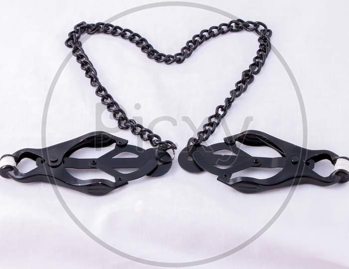 Black Clover Nipple Clamps With Connecting Chain Arranged In Heart Isolated On White
