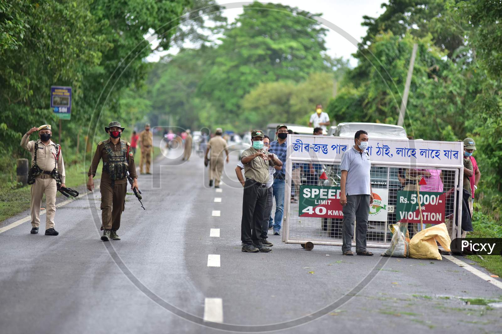 Forest officials stand guard on the National Highway 37 after a rhino strayed off from the Kaziranga National Park after it got flooded in Nagaon, Assam on July 18, 2020