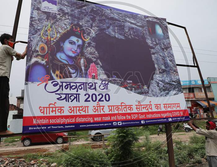 A labourer installs a hoarding outside Yatri Niwas Bhagwati Nagar ahead of the Amarnath Yatra 2020 in Jammu on July 19, 2020