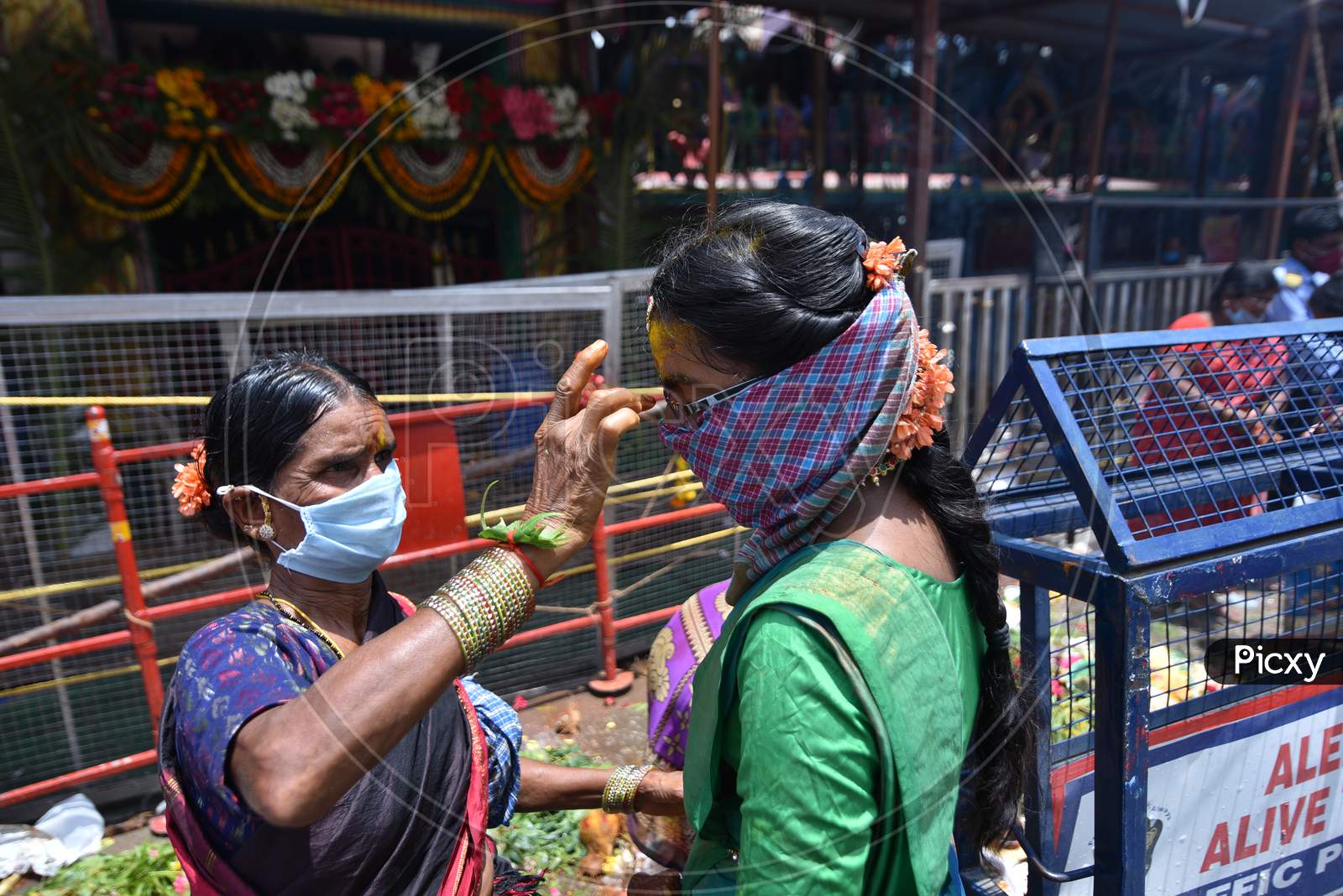 An elderly woman applies turmeric to a girl outside a closed Yellamma Pochamma Temple amid raising fears of coronavirus, July 19, 2020, Balkampet, Hyderabad, Bonalu 2020.