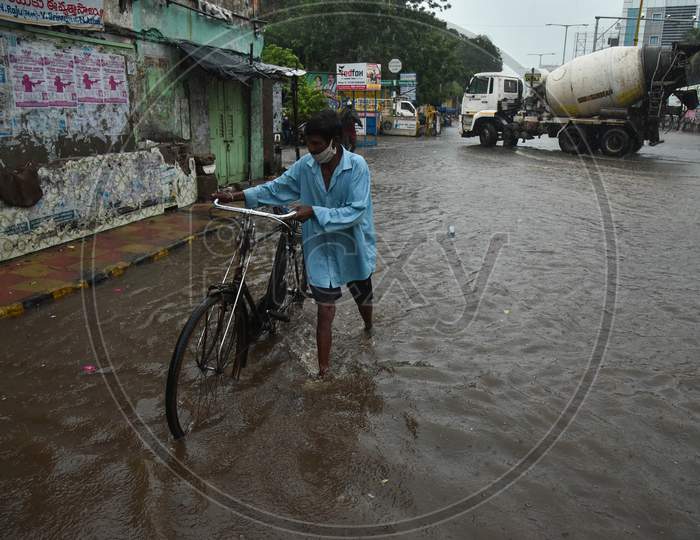 A Cyclist Wades Through A Water-Logged Road During Heavy Rain In Vijayawada.