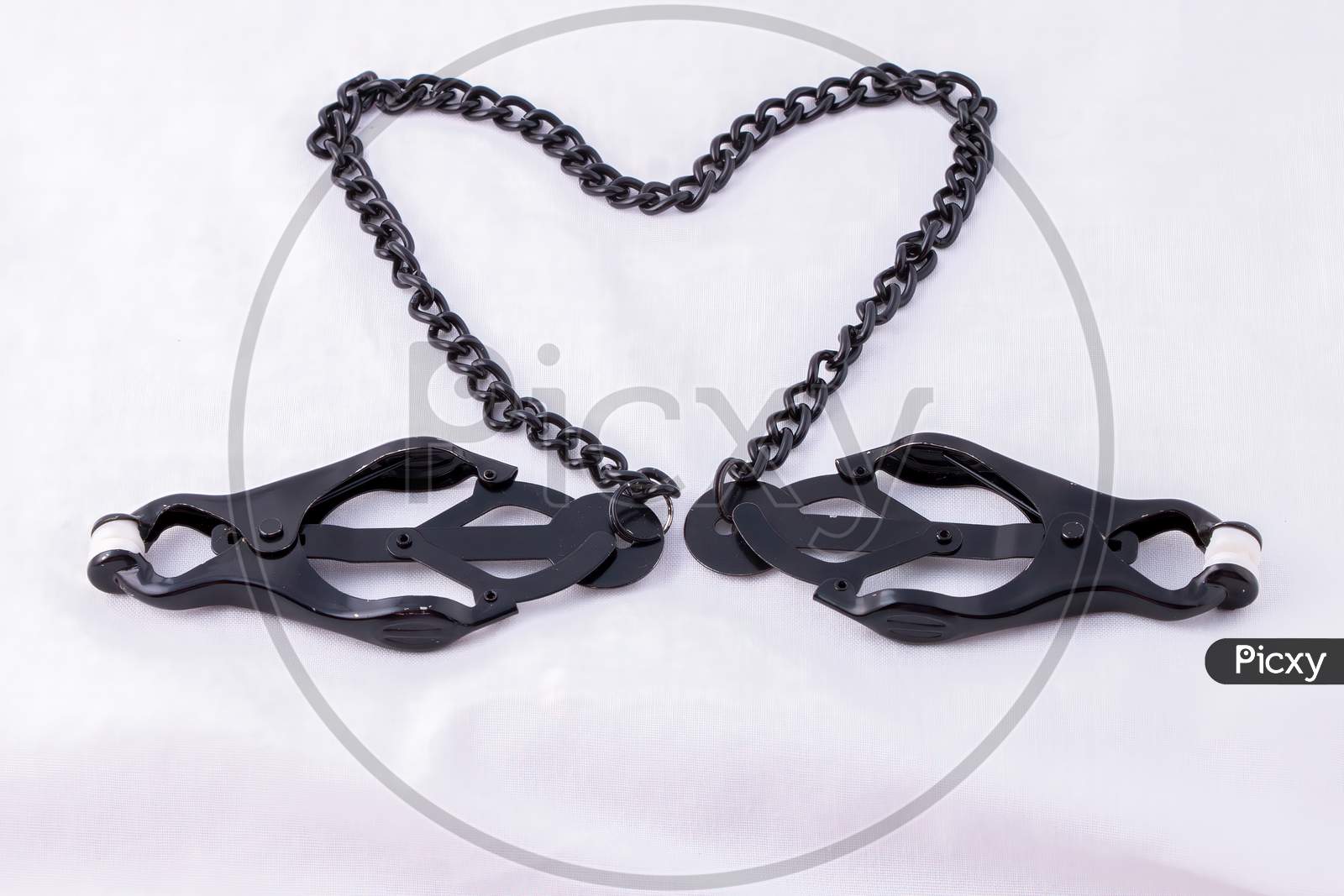 Black Clover Nipple Clamps With Connecting Chain Arranged In Heart Isolated On White