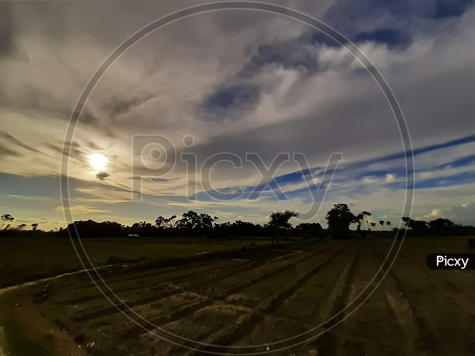 Agricultural Land In Rural India At Sunset. Black Clouds In The Blue Sky And A Pair Of Horizon Skies.