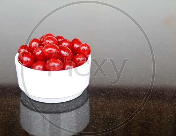 Red Color Cherry Fruits In A White Bowl Against Dark Background, With Copy Space, Caption
