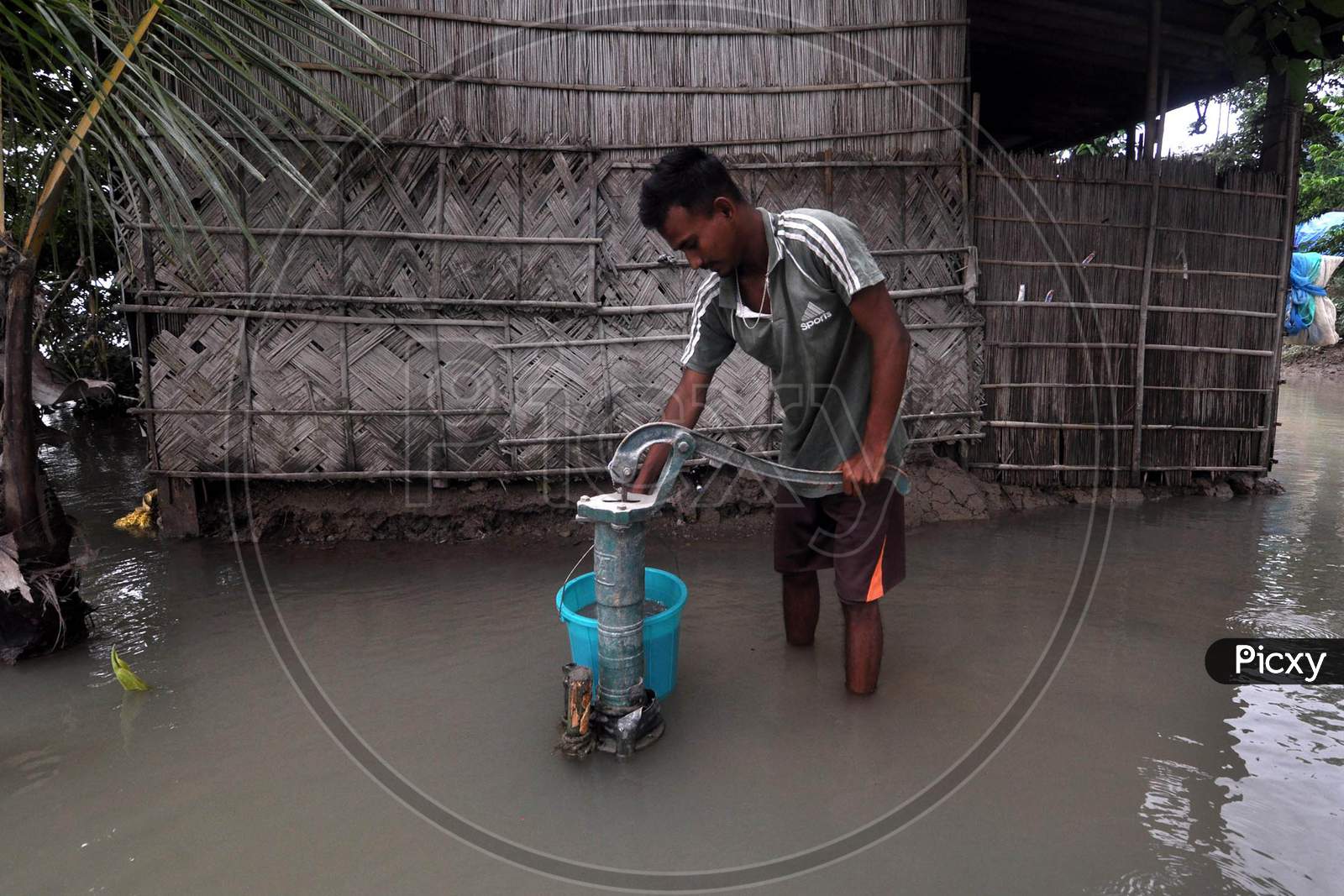 A boy uses a hand pump to collect drinking water in a flood-affected locality in Morigaon, Assam on July 18, 2020
