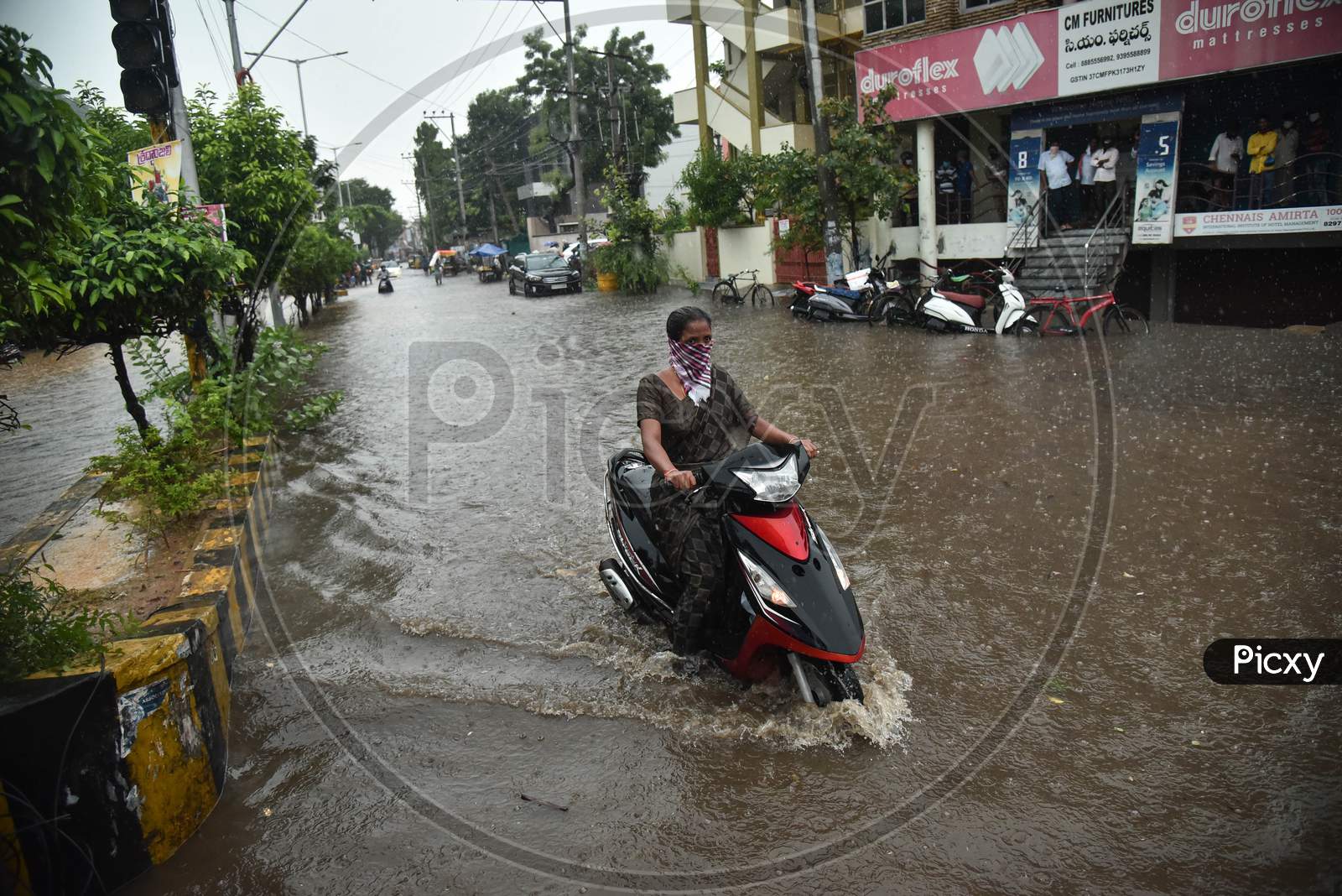 A Commuter Drives Through A Water-Logged Road During Heavy Rain In Vijayawada.