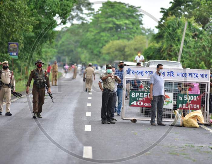 Forest officials stand guard on the National Highway 37 after a rhino strayed off from the Kaziranga National Park after it got flooded in Nagaon, Assam on July 18, 2020