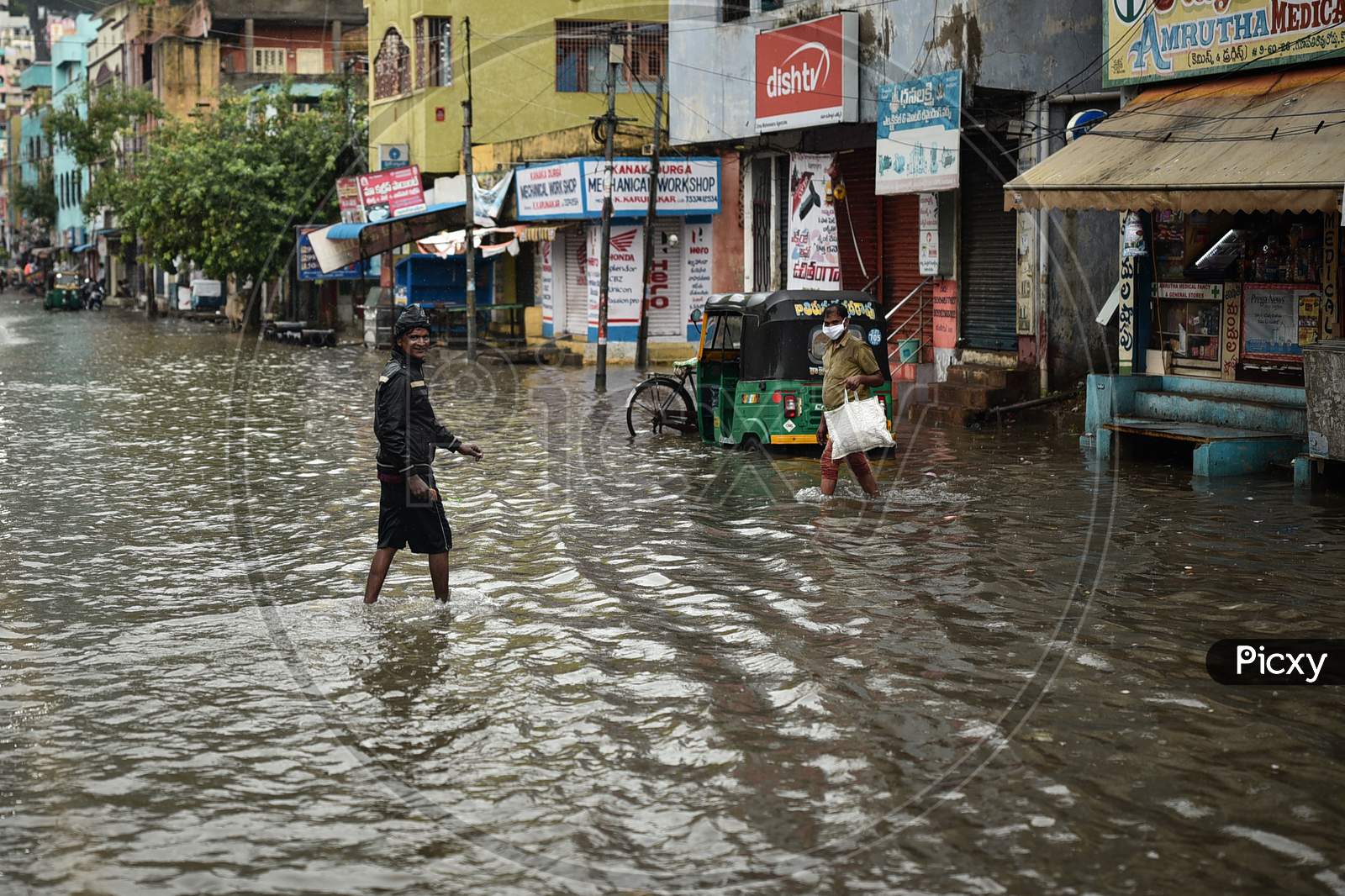 Image of People Wade Through A Water-Logged Road During Heavy Rain In ...