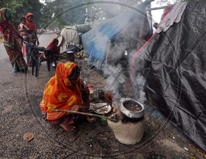 A women cooks food at a makeshift relief camps on the road at Sildubi in Morigaon, Assam on July 18, 2020