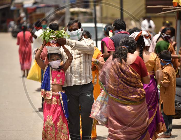A man helps his daughter carry a 'Bonam' offering at Balkampet yellamma Temple, Hyderabad, July 19, 2020.