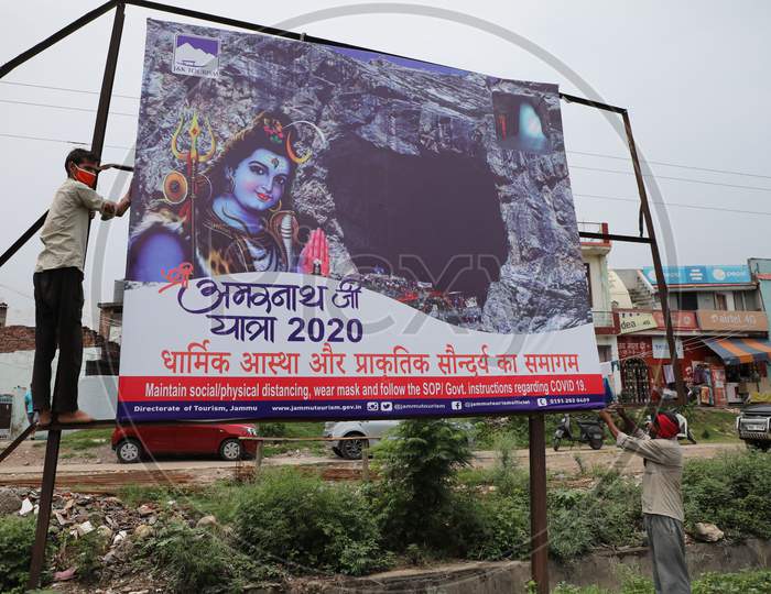 Labourers install a hoarding outside Yatri Niwas Bhagwati Nagar ahead of the Amarnath Yatra 2020 in Jammu on July 19, 2020