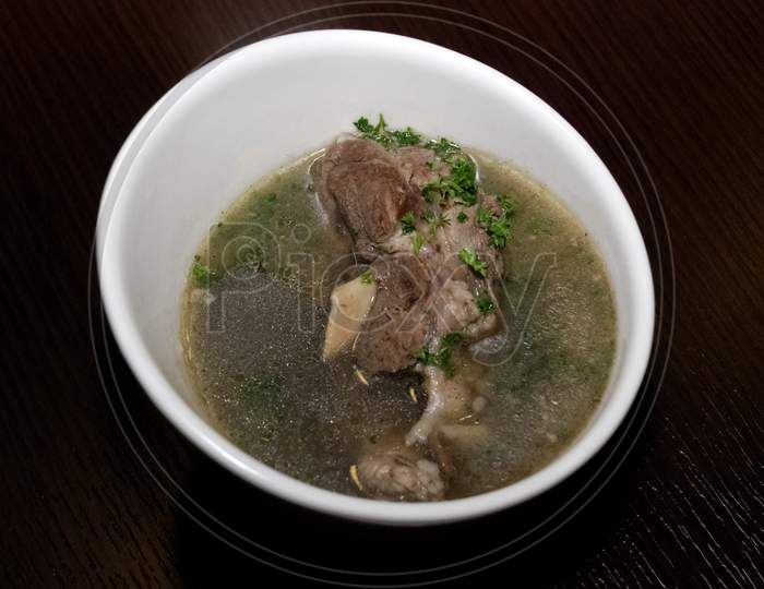 Meat In The Broth With Some Herbs Served In The White Bowl