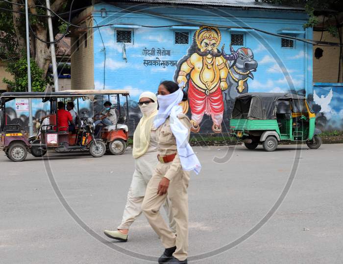Two women police officers walks in front of a wall which has a mural painting on it during the lockdown in Prayagraj on July 19, 2020