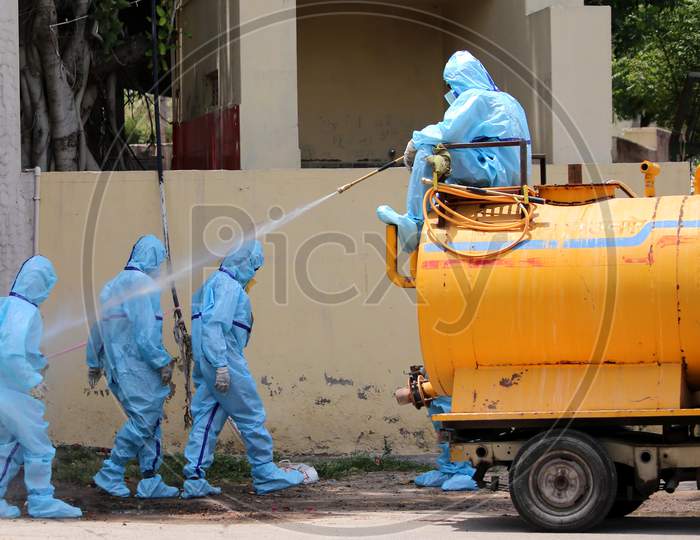 A municipal worker sprays disinfectant on his colleagues after they cremated a person who died of Covid-19 at a crematorium in Ajmer, Rajasthan on July 2, 2020.