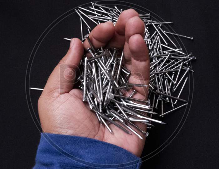 Closeup Shot Of A Male Hand Holding Steel Nails On Black Background