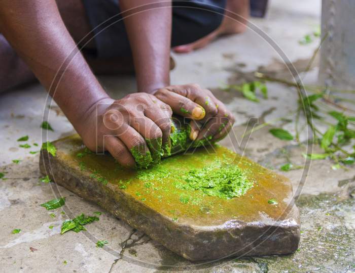 a medicine-man grinding neem leaves and turmeric for making medicine