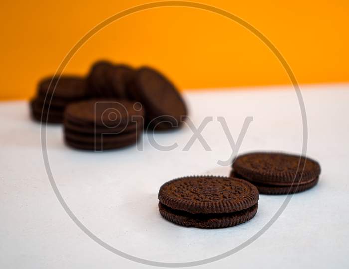 Chocolate Cookies Kept In A Pattern On A White Paper With A Yellow Background