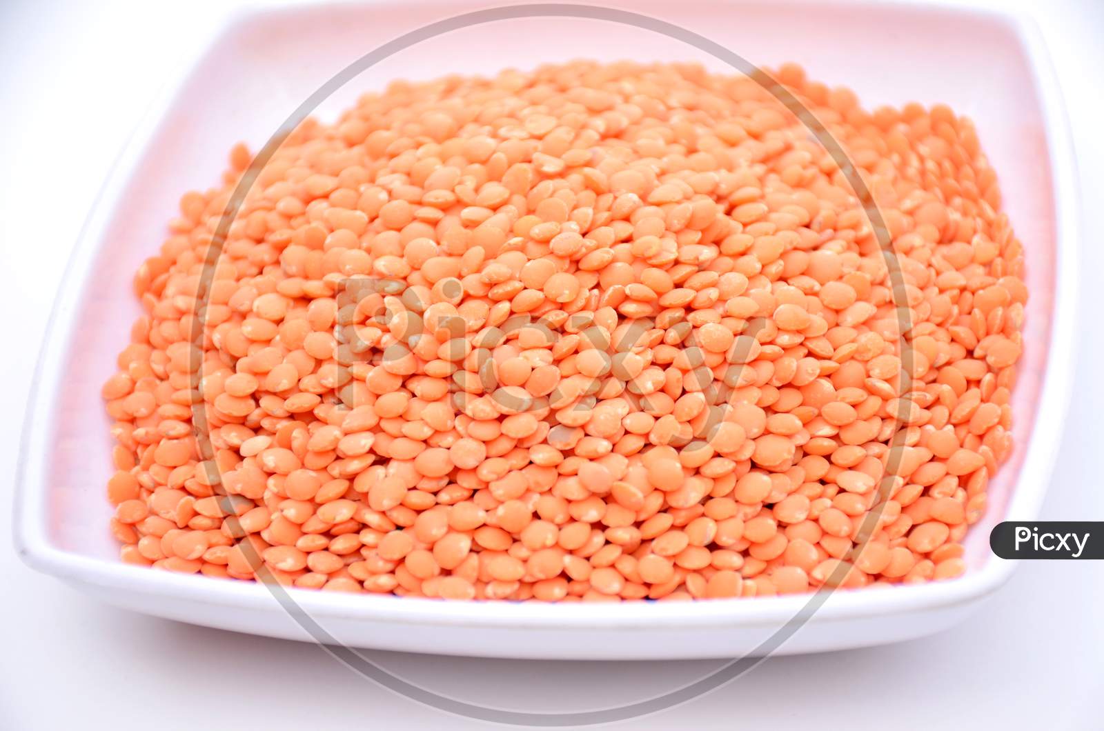 the red lentils in the white plate isolated on white background.