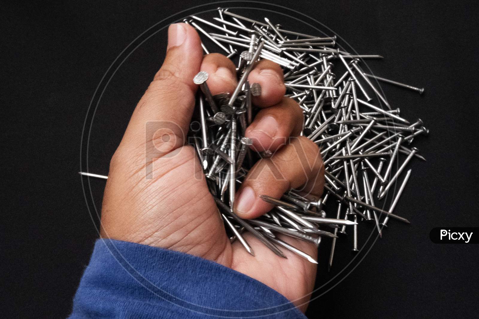 Closeup Shot Of A Male Hand Holding Steel Nails On Black Background