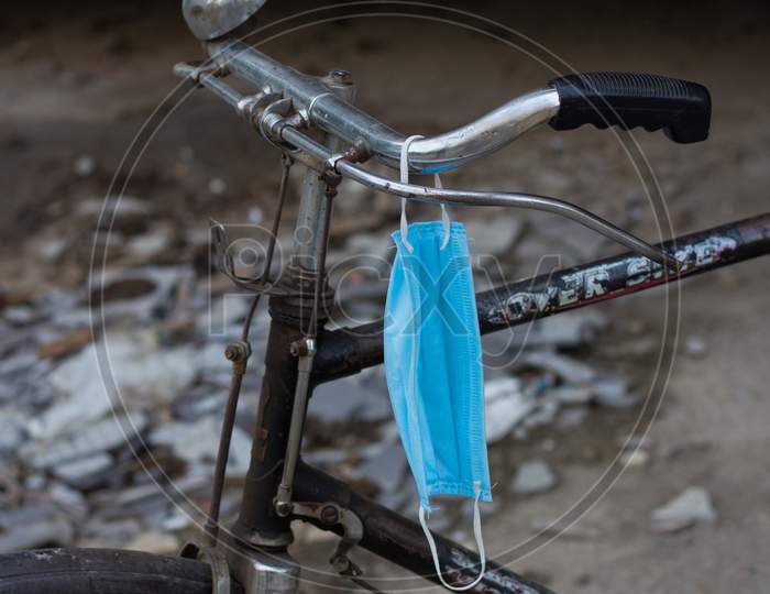 Disposable Medical Mask Hanging On A Cycle'S Handle.