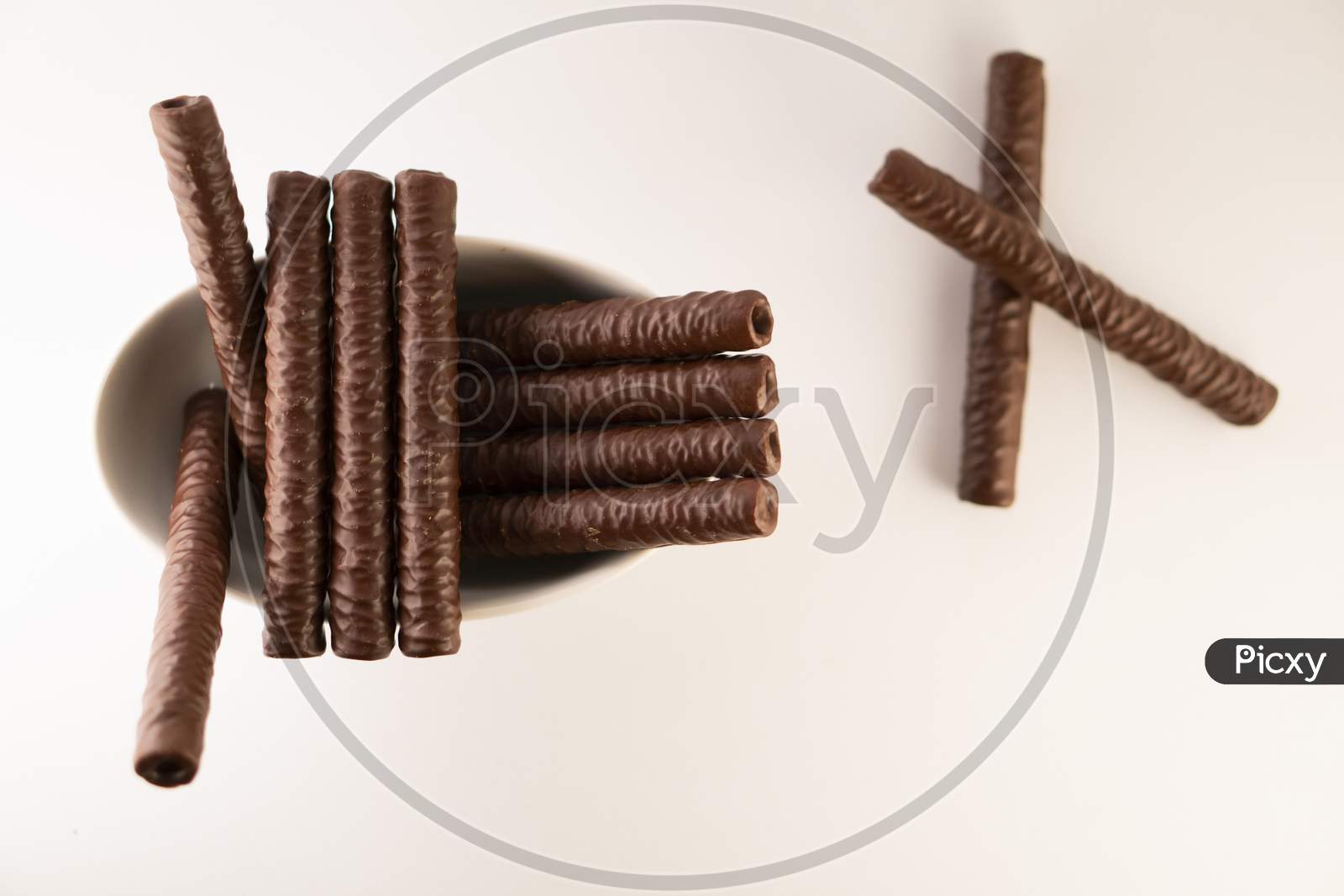 chocolate sticks in a bowl on a white background.