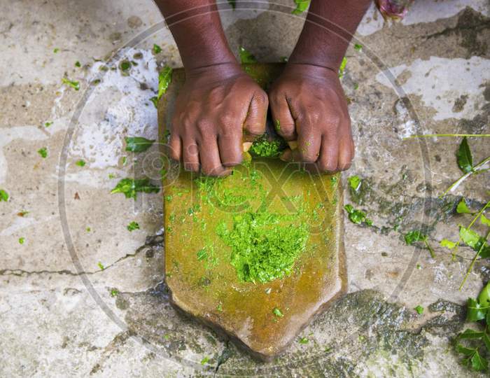 a medicine-man grinding neem leaves and turmeric for making medicine