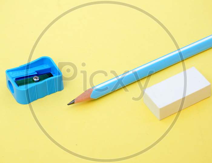 the sky blue wooden pencil with sharpner and eraser on yellow background.