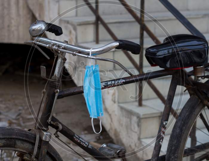 Disposable Medical Mask Hanging On A Cycle'S Handle.