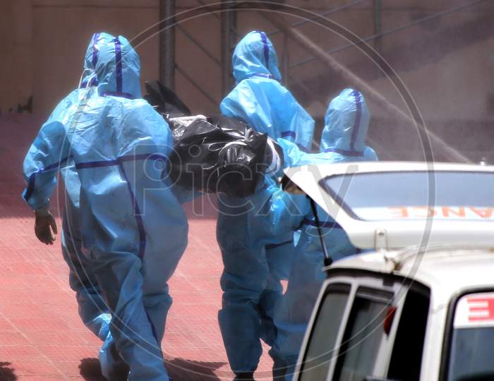 Health workers in hazmat suits carry the dead body of a person who died due to coronavirus infection at a crematorium in Rajasthan on July 02, 2020.