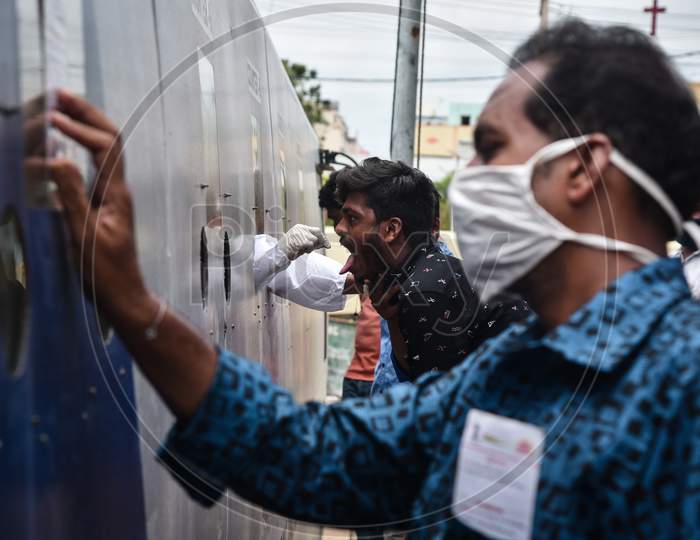 A medic collects a swab sample of a man for the COVID-19 test from a mobile swab collection vehicle in Vijayawada.