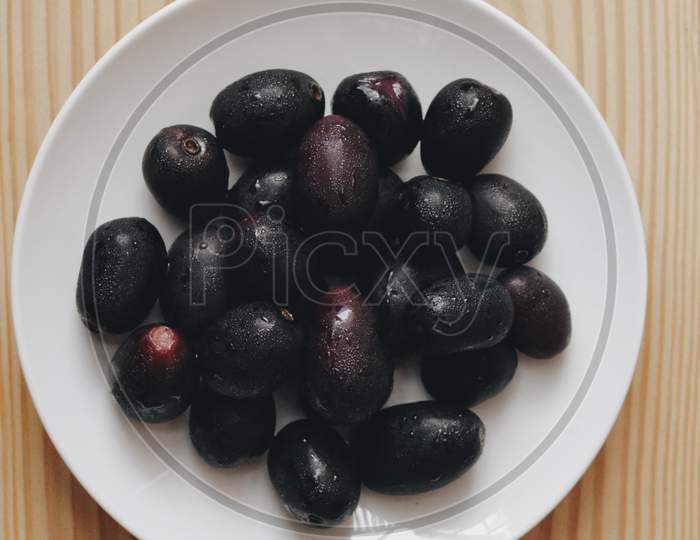Picture of Java Plum fruit on white plate, indian jamun