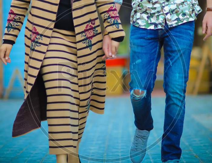 Male And A Female Holding Hands While Walking In Modern Clothing