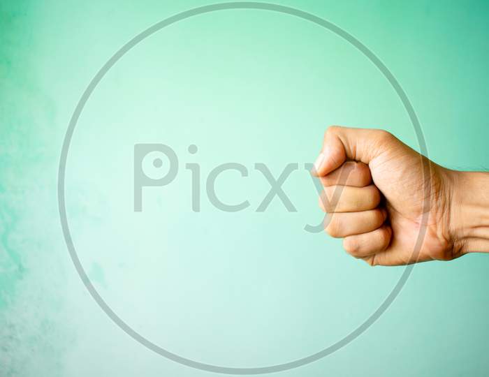 Hand Of Man With Fist On Green Background.