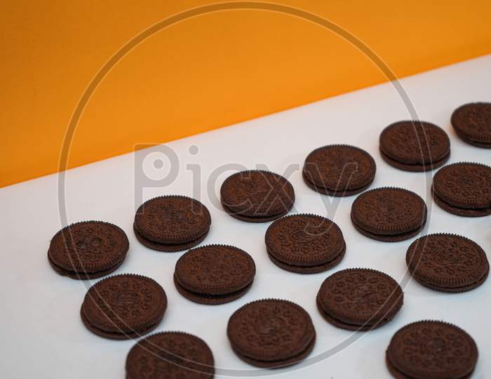 Chocolate Cookies Kept In A Pattern On A White Paper With A Yellow Background