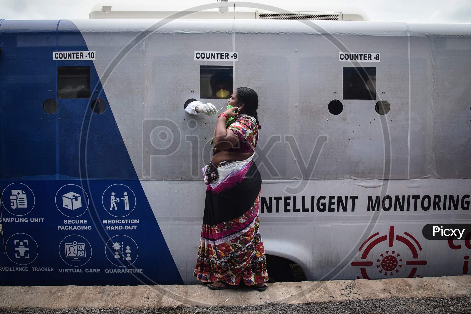 A medic collects a swab sample of a woman for the COVID-19 test from a mobile swab collection vehicle in Vijayawada.