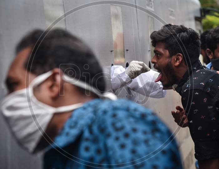 A medic collects a swab sample of a man for the COVID-19 test from a mobile swab collection vehicle in Vijayawada.