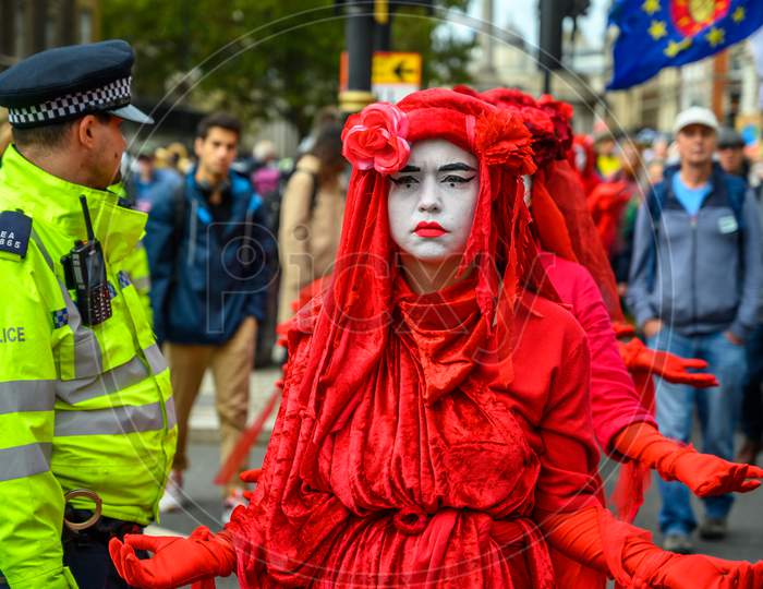Close Up Of The Extinction Rebellion Red Brigade Protesters Passing A Metropolitan Police Officer