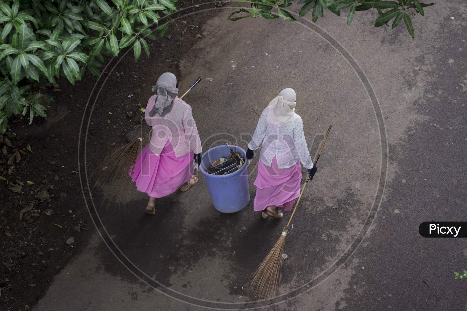 Road Sweeper ladies cleaning city roads with broom