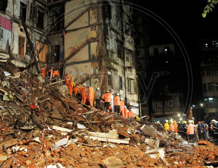 National Disaster Response Force (NDRF) and fire brigade personnel look for survivors trapped in the debris after part of a residential building collapsed following heavy rains in Mumbai, India, July 16, 2020.