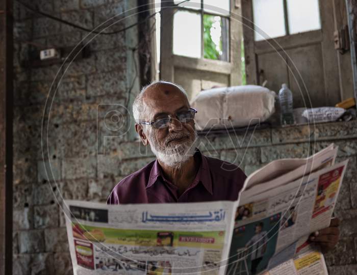 Old man reading local newspaper in marketplace