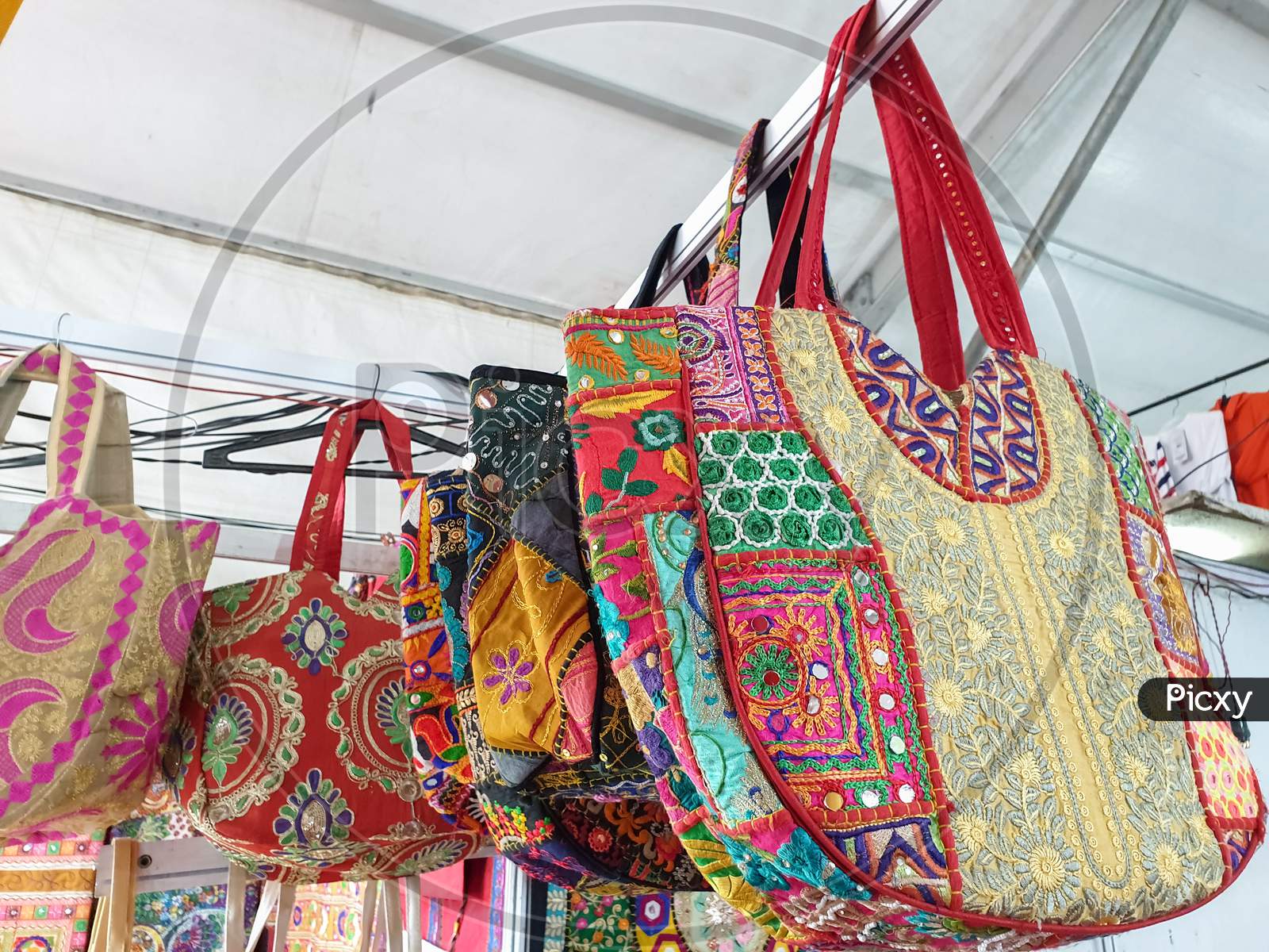 Mandi, Himachal Pradesh / India - 03 07 2020: Photo of variety of colorful Rajasthani artwork handbags hanging in the store for sale