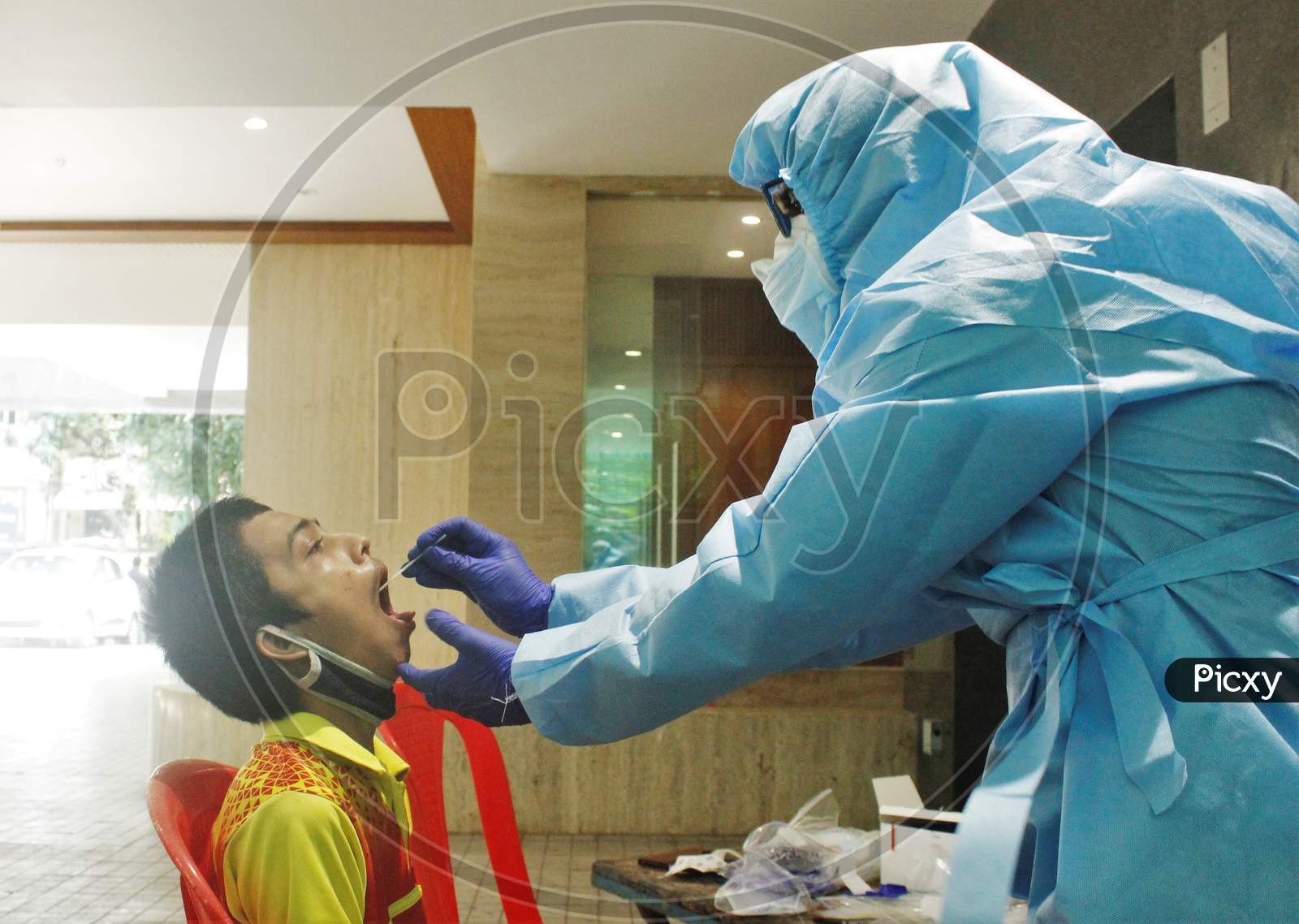 A healthcare worker wearing personal protective equipment (PPE) collects a swab sample from a resident of a locality during a check-up campaign for the coronavirus disease (COVID-19), in Mumbai, India on July 20, 2020.