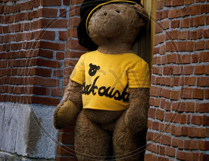 Krakow, Poland - May 03, 2015: A Huge Teddy Bear In Yellow T Shirt And A Cap Appears To Be Stepping Down From A Random Shop