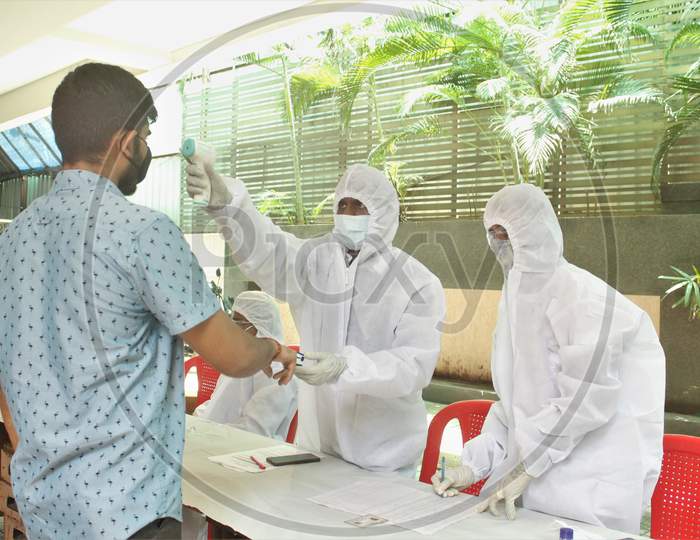 A healthcare worker wearing personal protective equipment (PPE) measures the pulse and checks the temperature of a resident of a locality during a check-up campaign for the coronavirus disease (COVID-19), in Mumbai, India on July 20, 2020.
