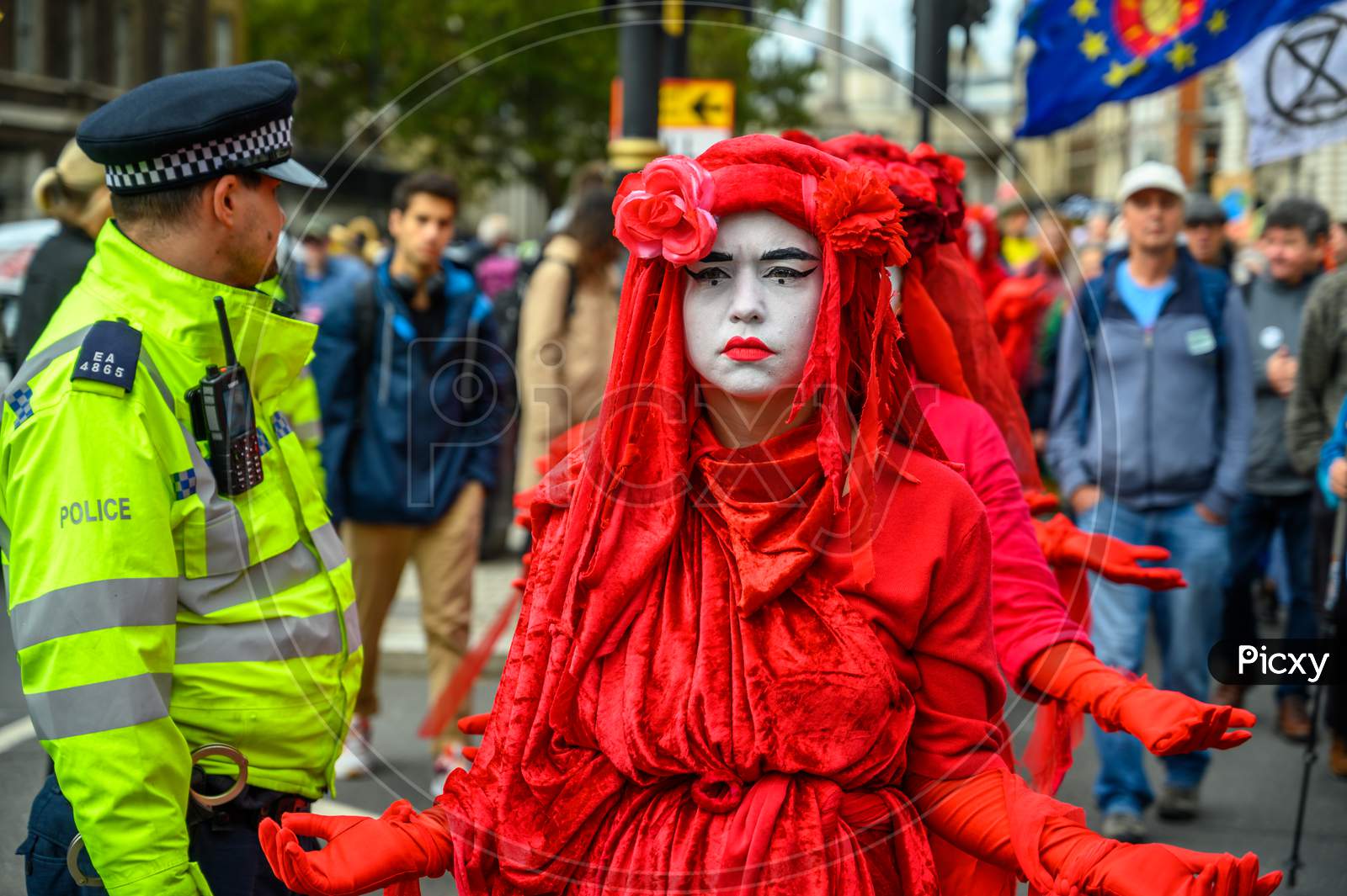 Close Up Of The Extinction Rebellion Red Brigade Protesters Passing A Metropolitan Police Officer