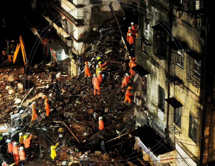 National Disaster Response Force (NDRF) and fire brigade personnel look for survivors trapped in the debris after part of a residential building collapsed following heavy rains in Mumbai, India, July 16, 2020.
