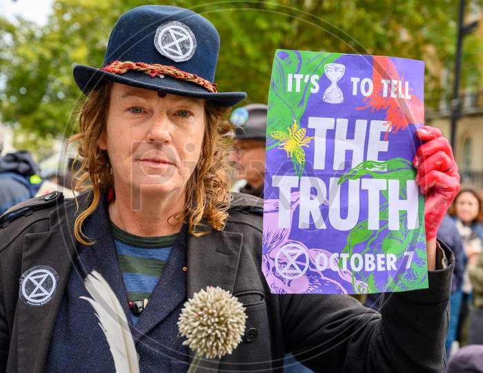 Close Up Of Eccentric Extinction Rebellion Protester Holding A Protest Sign And Looking Directly Into The Camera