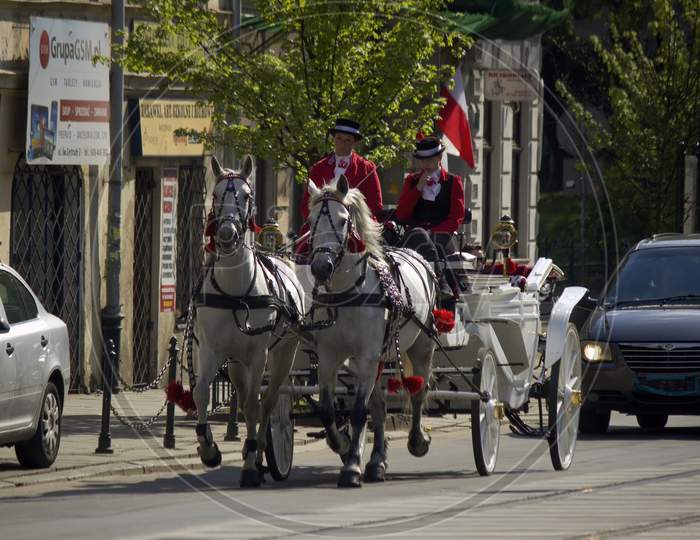 Krakow, Poland - May 03, 2015: Moving Horse Cart Or Carriage Ride On A Road Drive By Two Ladies In Traditional Clothing